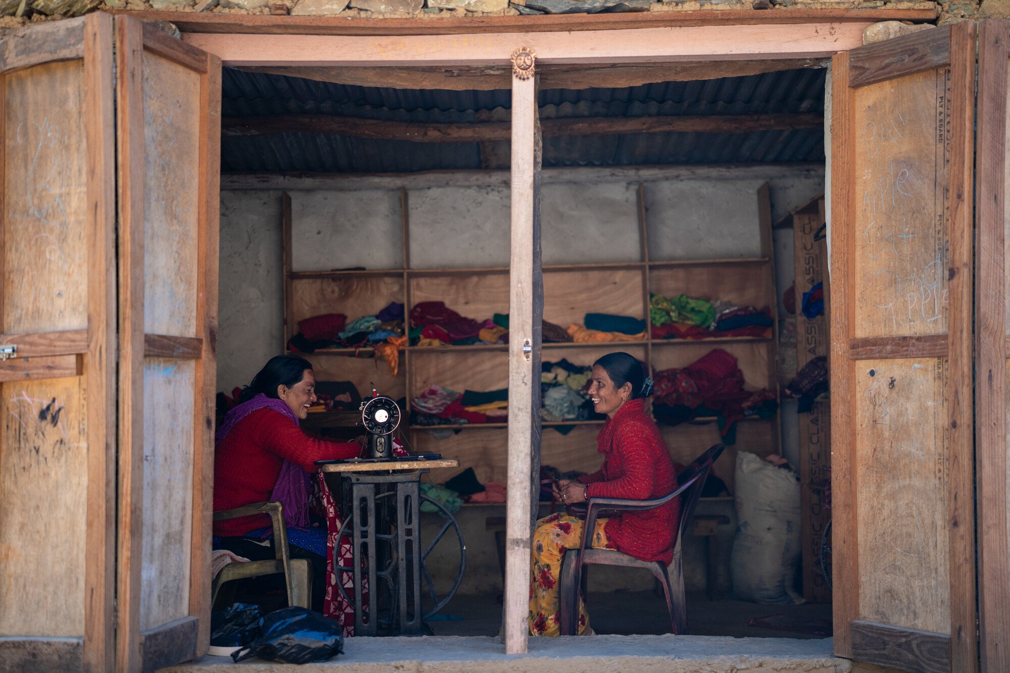  Reshma Kumari Nepali (left) works on her sewing machine in her shop while she meets with Pramila Bhul. Reshma says the funds from the ward council budget that paid for her training and got her a sewing machine helped her start her tailoring business. 