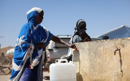 Amina Sahardid fills a jerry can with water from a newly installed tap served by a well rehabilitated by Oxfam near her home.