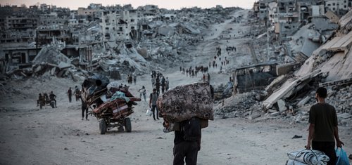 Palestinians displaced by conflict in Gaza walk across rubble-strewn streets to Jabalia, an area heavily damaged since the war began in October 2023.