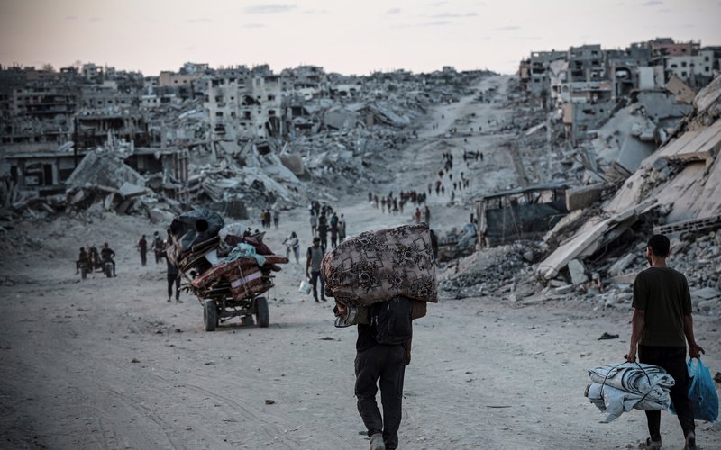 Palestinians displaced by conflict in Gaza walk across rubble-strewn streets to Jabalia, an area heavily damaged since the war began in October 2023.