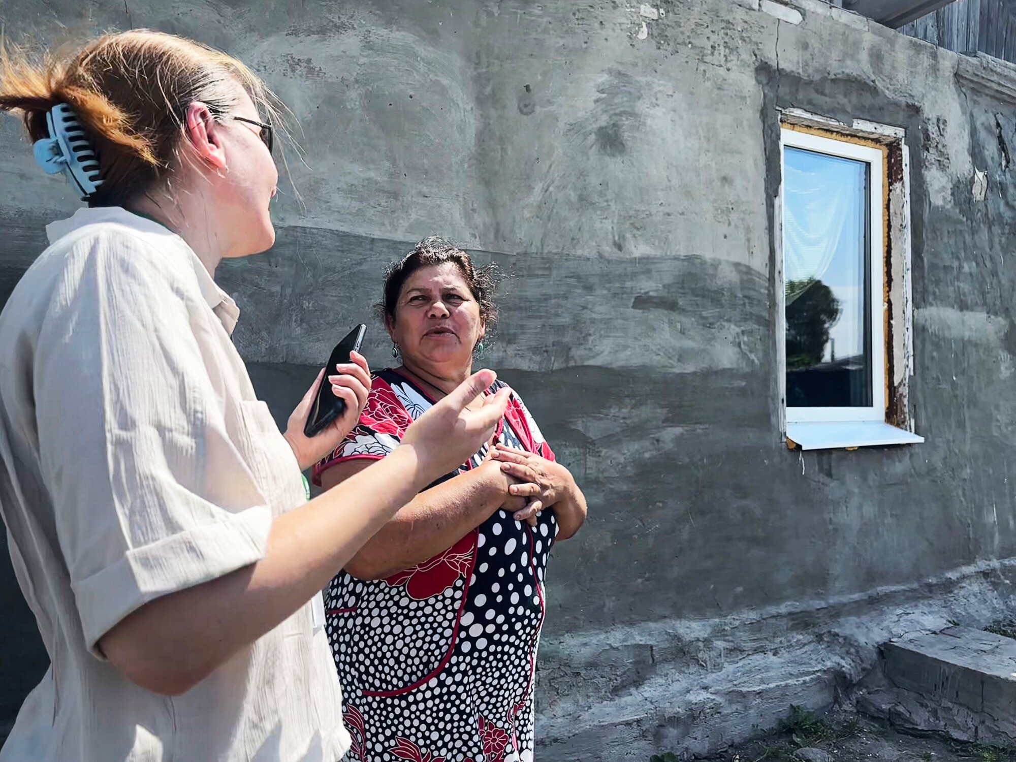  Oxfam program officer Iryna Kharlan-Plamenevska (left) inspects repairs on the home of Ratha Yurenko, which was damaged in fighting in Kharkiv. 