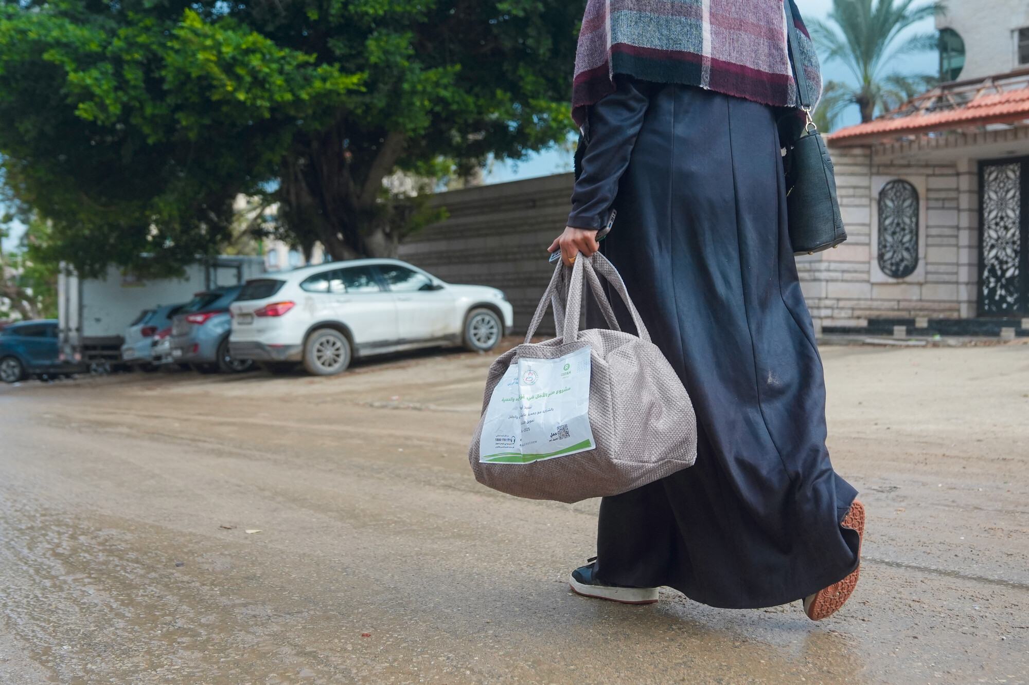  A Palestinian woman in Gaza walks home with a bag of hygiene items provided by Oxfam and the Aisha Association for Women and Child Protection. 