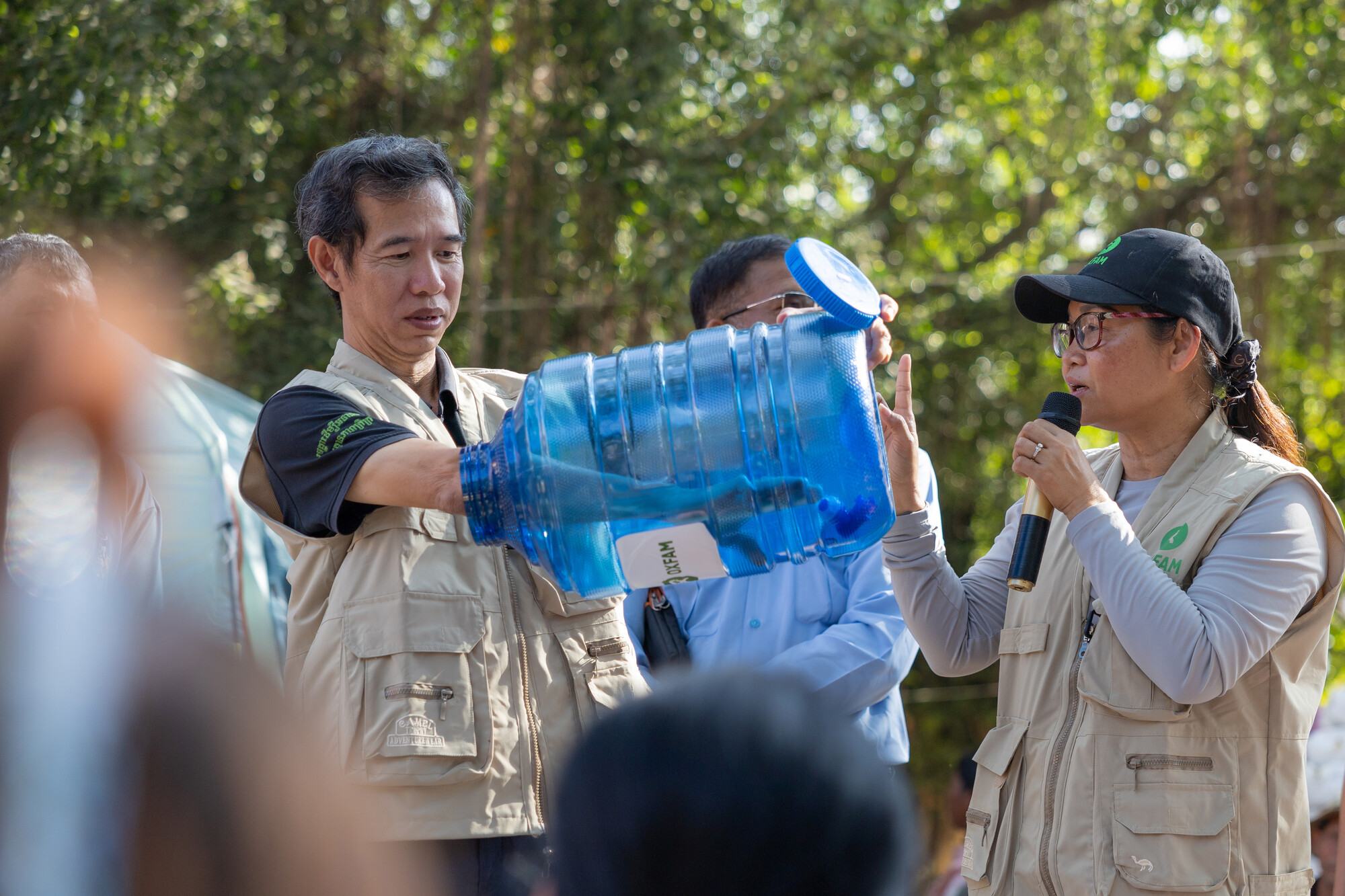 Oxfam Cambodia National Director Sophoan Phean (right) and Khim Sok, natural resource governance program manager, talk with families as teams distribute water containers, rice, and dignity kits. The latter include basic items such as flashlights, detergen 