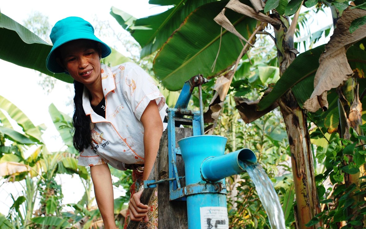 Yem Neang pumps water from well to water the plants in her garden