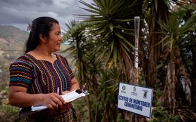 Doña Brenda Alicia Guanché Manuel, 35 years old, monitors the rain gauge outside her home in Chixim, Baja Verapaz, Guatemala. The daily weather observations she collects help small local farmers make informed decisions about planting in the Dry Corridor.