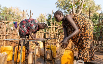 Two women fill water jugs in the Gambella refugee camp in Ethiopia.
